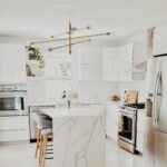 A bright, modern kitchen featuring white cabinetry, stainless steel appliances, and minimalist decor.