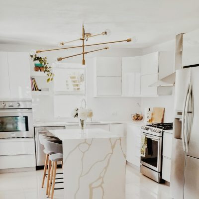 A bright, modern kitchen featuring white cabinetry, stainless steel appliances, and minimalist decor.